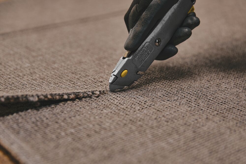 6 and 3 eighths inch Quick change retractable utility knife cutting woolen sheet. 6 and 3 eighths inch Quick change retractable utility knife cutting woolen sheet.