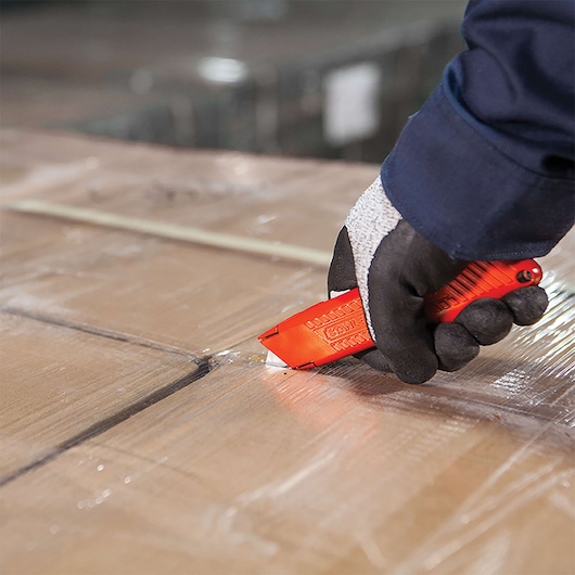 Overhead view of Self retracting safety utility knife opening cardboard box.