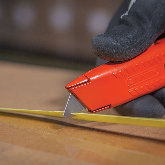 Closeup of Self retracting safety utility knife cutting tape.