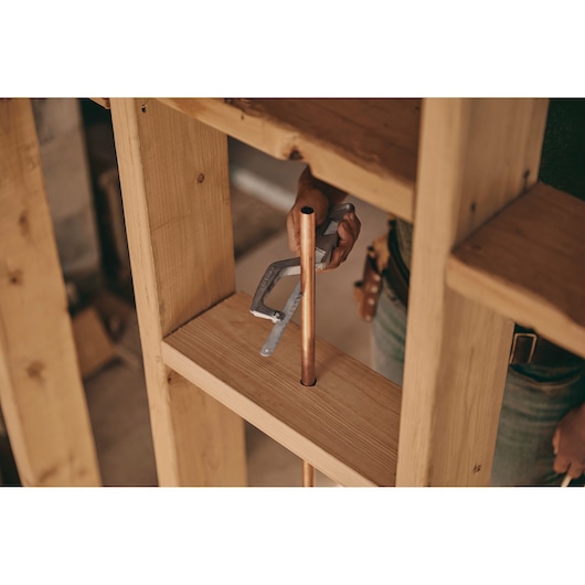 10 inch metal mini-hack utility saw being used to saw a pipe.