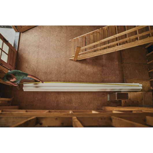 25 foot FATMAX classic tape measure being used by a person to measure pipe length.