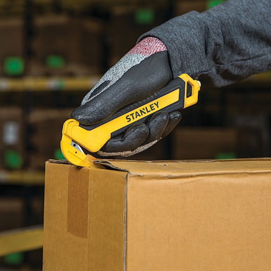 SINGLE SIDED BI MATERIAL PULL CUTTER being used for opening cardboard box.