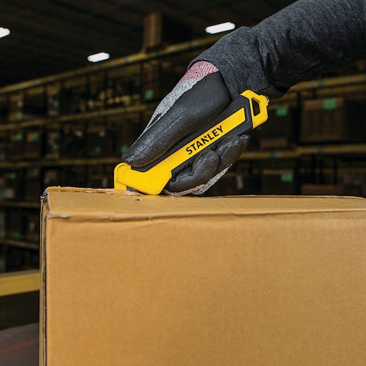 SINGLE SIDED BI MATERIAL PULL CUTTER being used for opening cardboard box from round side.