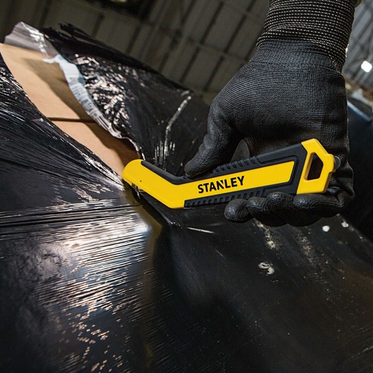 SINGLE SIDED ROUND TIP BI MATERIAL PULL CUTTER being used for cutting plastic packing on cardboard boxes.