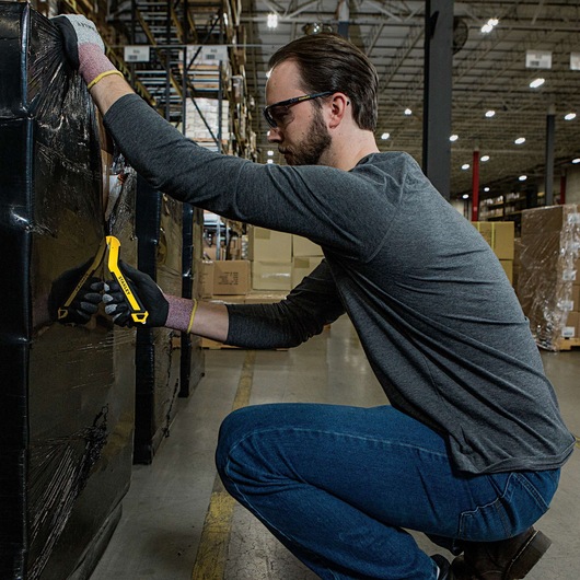 SINGLE SIDED ROUND TIP BI MATERIAL PULL CUTTER being used for cutting plastic packing on cardboard boxes by person.