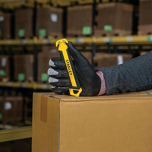 DOUBLE SIDED BI MATERIAL PULL CUTTER being used for opening cardboard package.