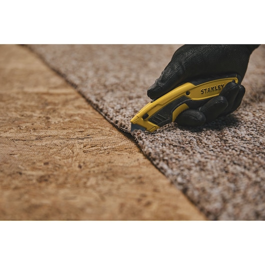 Retractable Utility Knife being used for cutting carpet.