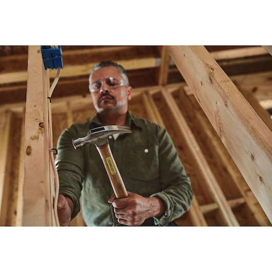 16 OUNCE RIP CLAW WOOD HANDLE HAMMER in use by person.