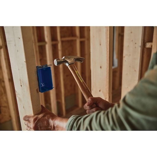 16 OUNCE RIP CLAW WOOD HANDLE HAMMER being used to drive nail into wood.