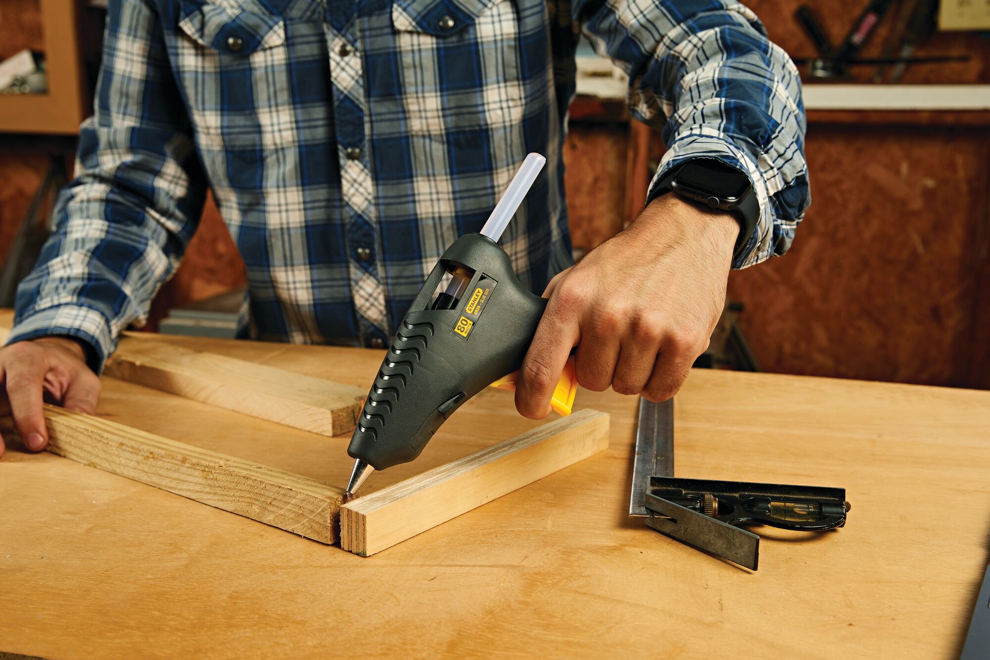 8 half inch trigger feed standard dual melt glue gun being used by a person to join wood sticks together.