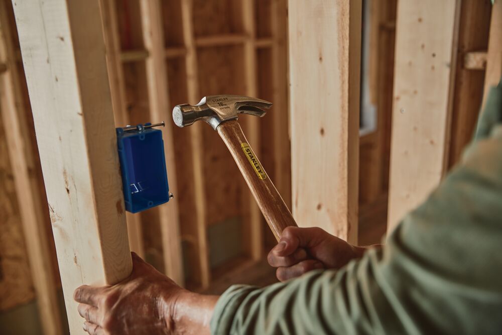 16 OUNCE RIP CLAW WOOD HANDLE HAMMER being used to drive nail into wood.